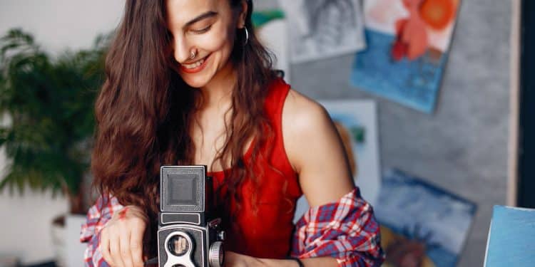 Mulher usa câmera analógica antiga, exemplo de profissões fora de moda que ainda remuneram bem