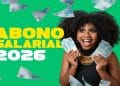 Mulher sorri segurando notas de R$ 100 ao lado da arte "Abono Salarial 2026", em imagem que ilustra quem tem direito ao benefício, incluindo quem ganhou o salário mínimo em 2024.