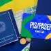 Carteira de trabalho, dinheiro e cartão PIS/Pasep da Caixa sobre fundo com cores do Brasil.