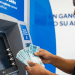 Homem conta cédulas de R$ 100 em frente a caixa eletrônico, representando o saque de até R$ 6.220 do FGTS por calamidade em 2026.