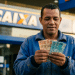 Trabalhador conta cédulas de R$ 50 e R$ 100 em frente a uma agência da Caixa após o Saque Calamidade do FGTS