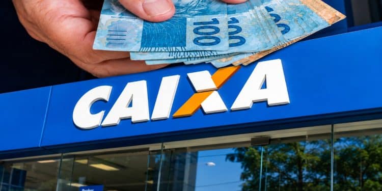 Mão segurando várias notas de R$ 100 sobre a fachada de uma agência da CAIXA, representando o pagamento do Pé-de-Meia.