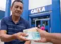 Trabalhador recebendo cédulas de real em frente a uma agência da Caixa, representando o saque de até R$ 1.621 do PIS/Pasep.