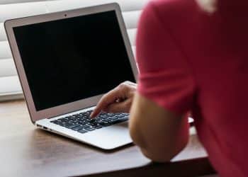 Monitor de computador exibe ilustração ampliada de um vírus sobre mesa com teclado