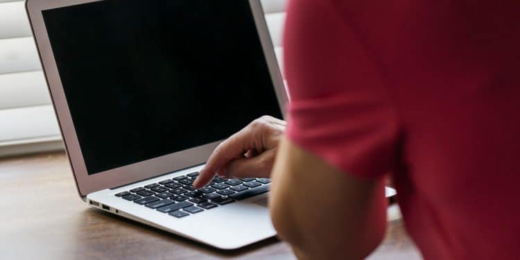 Monitor de computador exibe ilustração ampliada de um vírus sobre mesa com teclado