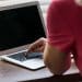 Monitor de computador exibe ilustração ampliada de um vírus sobre mesa com teclado