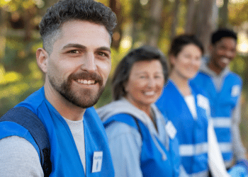 Agentes de saúde sorridentes em ação voluntária em área arborizada.