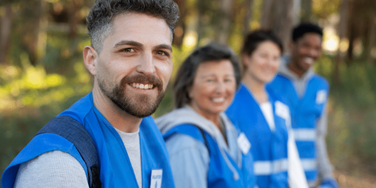 Agentes de saúde sorridentes em ação voluntária em área arborizada.