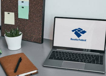 Logo da Receita Federal exibido em notebook sobre mesa de trabalho moderna.
