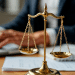 Balança dourada da justiça em foco próximo a pessoa digitando.