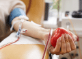 Doação de sangue com foco na coleta e coração de borracha vermelho.