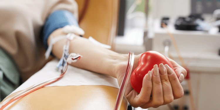 Doação de sangue com foco na coleta e coração de borracha vermelho.