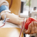 Doação de sangue com foco na coleta e coração de borracha vermelho.
