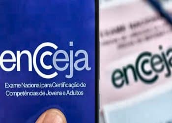 Tela de celular exibe logo Encceja com fundo azul e texto oficial, mão segura aparelho, simbolizando as principais datas do Encceja 2026