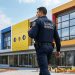 Guarda municipal patrulha pátio escolar em frente a escola colorida.