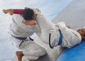 Lutadores executam finalização no tatame durante treino de jiu-jitsu.