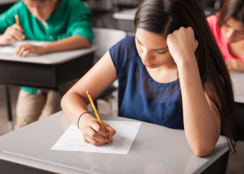 Estudantes concentrados realizando prova em sala de aula.