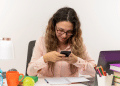 Jovem estudante distraída com celular em dia de estudos.