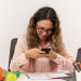 Jovem estudante distraída com celular em dia de estudos.