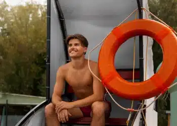 Salva-vidas sentado em embarcação de resgate com boia de segurança em ambiente aquático.