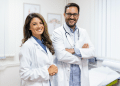 Médicos sorridentes em consultório iluminado em ambiente hospitalar.