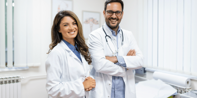 Médicos sorridentes em consultório iluminado em ambiente hospitalar.