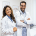 Médicos sorridentes em consultório iluminado em ambiente hospitalar.