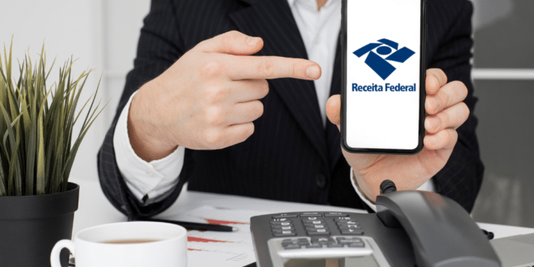Executivo aponta para aplicativo da Receita Federal em smartphone.