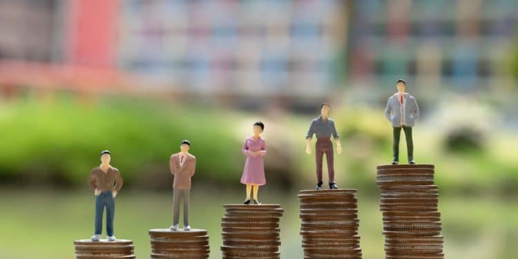 Figuras em miniatura sobre pilhas de moedas de tamanhos crescentes, representando diferenças salariais entre profissões