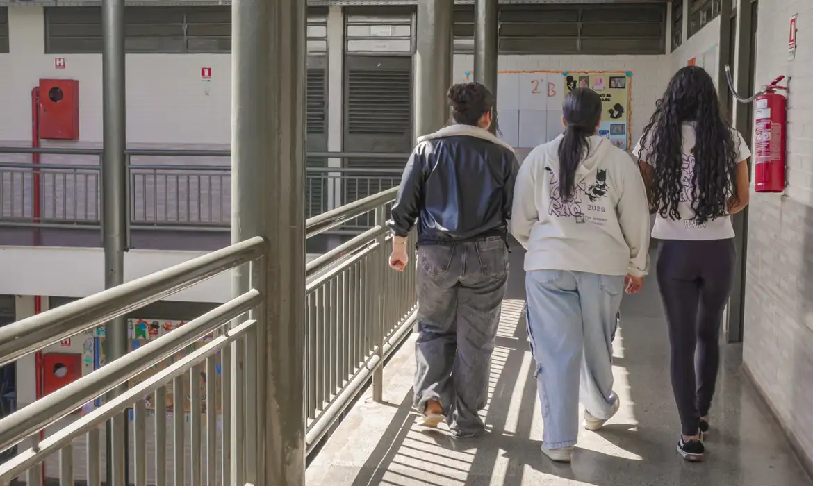Imagem de estudantes caminhando por um corredor de escola, tema da matéria sobre o recurso do atendimento especializado do Enem 2026.