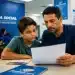 Pai e filho lendo documento durante atendimento no INSS, representando a conferência dos direitos do MEI além da aposentadoria e dos benefícios previdenciários destinados à família.