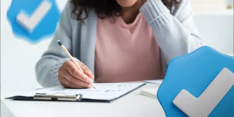 Estudante escreve em prancheta ao lado de ícones azuis de selo de verificação, simbolizando benefícios garantidos pelo Enem