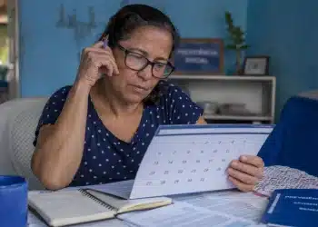 Mulher consultando calendário em casa, representando as datas de pagamento do INSS de julho a dezembro de 2026.