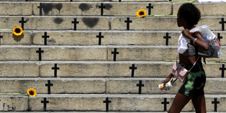 Cruzes pretas e flores em escadaria simbolizam vítimas da violência no Brasil.