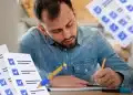 Homem de camisa jeans escreve em caderno enquanto estuda para concurso público, com ilustrações de checklist ao redor