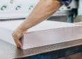 Trabalhador posiciona na guilhotina de uma gráfica um bloco de folhas de papel branco, conjunto conhecido como resma, que reúne 500 folhas