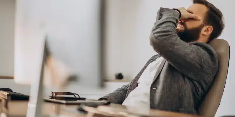 Homem em ambiente de escritório demonstrando cansaço e sobrecarga emocional após rotina intensa de trabalho e responsabilidades.