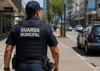 Guarda municipal fardado caminhando em via urbana, representando o concurso da Guarda Municipal de Balneário Piçarras (SC) com inscrições abertas.