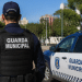 Guarda Municipal de costas em patrulhamento ao lado de viatura oficial em área urbana.