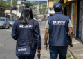 Dois agentes do IBGE caminhando por uma rua durante atividade de campo.