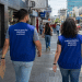 Dois fiscais do Procon de Alagoas caminham por uma rua comercial durante atividade de fiscalização.