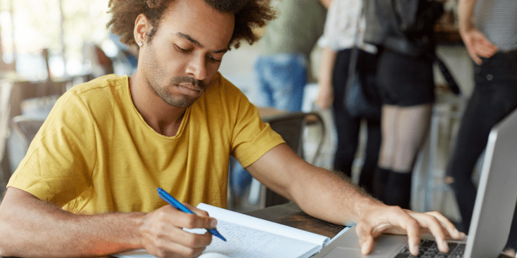 Candidato estuda com caderno e notebook para concursos públicos com vagas em São Paulo e Minas Gerais.
