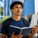 Estudante com caderno e documento em frente a uma universidade, ilustrando as condições para concorrer ao Prouni e ao Fies 2026