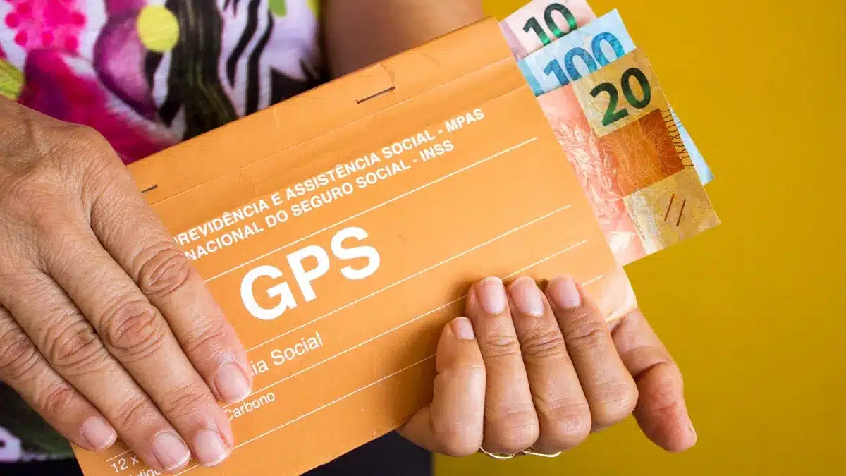 Mãos preenchendo guias GPS no balcão para manter a qualidade de segurado do INSS ativa