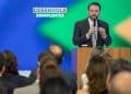 Homem de terno discursa em púlpito diante de plateia sob painel do Desenrola Adimplentes em evento do governo