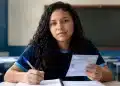 Estudante brasileiro em sala de aula segurando cartão de inscrição e caneta, em preparação para o Enem