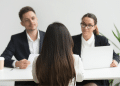 Candidata participa de entrevista de emprego diante de dois recrutadores.