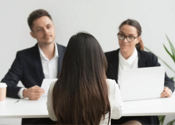 Candidata participa de entrevista de emprego diante de dois recrutadores.
