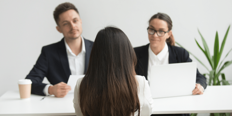Candidata participa de entrevista de emprego diante de dois recrutadores.
