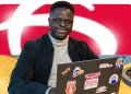 Jovem participante do Programa de Estágio Bradesco em frente ao computador, com logo do Bradesco ao fundo.
